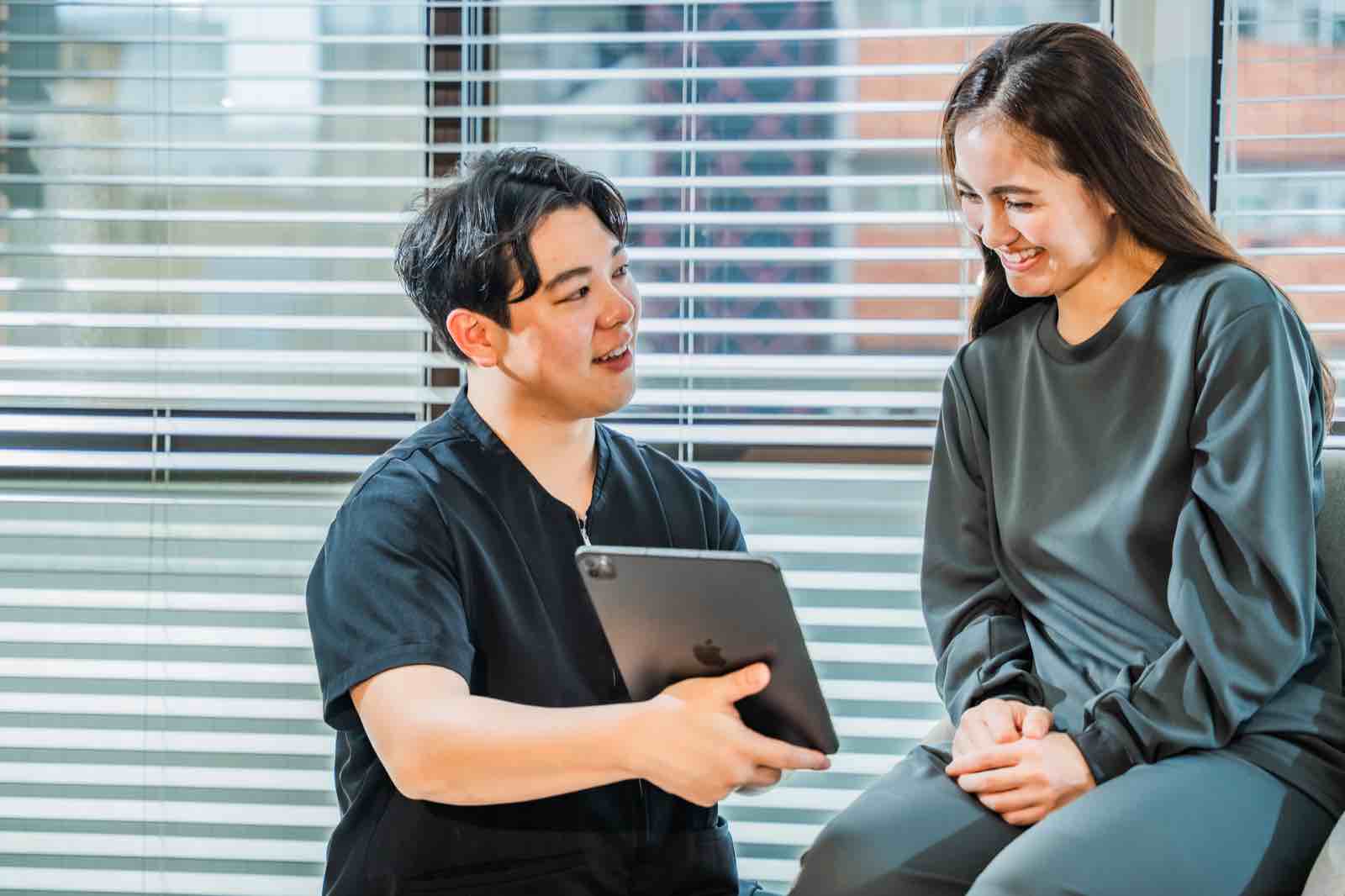 iPadを見ながら体の状態について説明する施術者と来店者